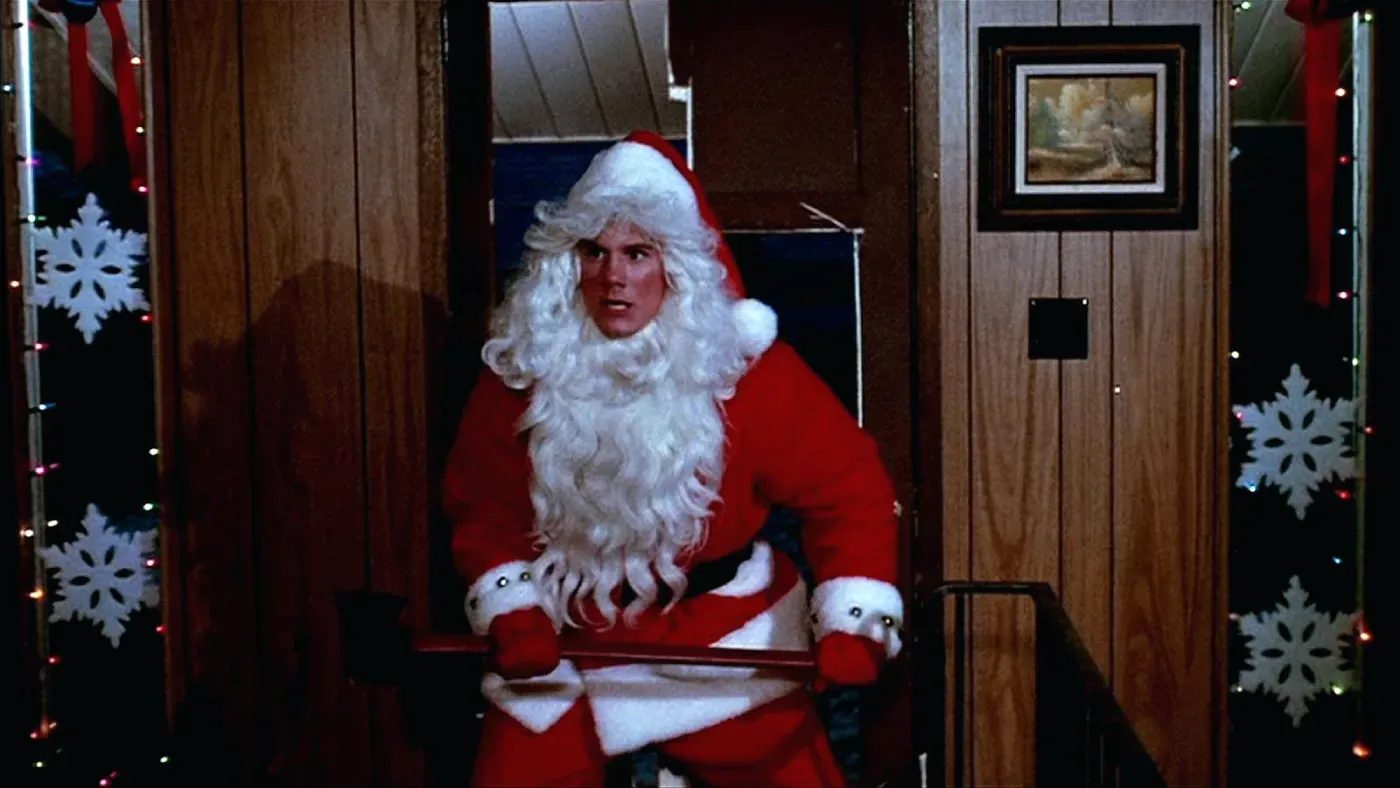 Een moment uit de kersthorrorfilm Silent Night, Deadly Night met een kerstman en een bijl.