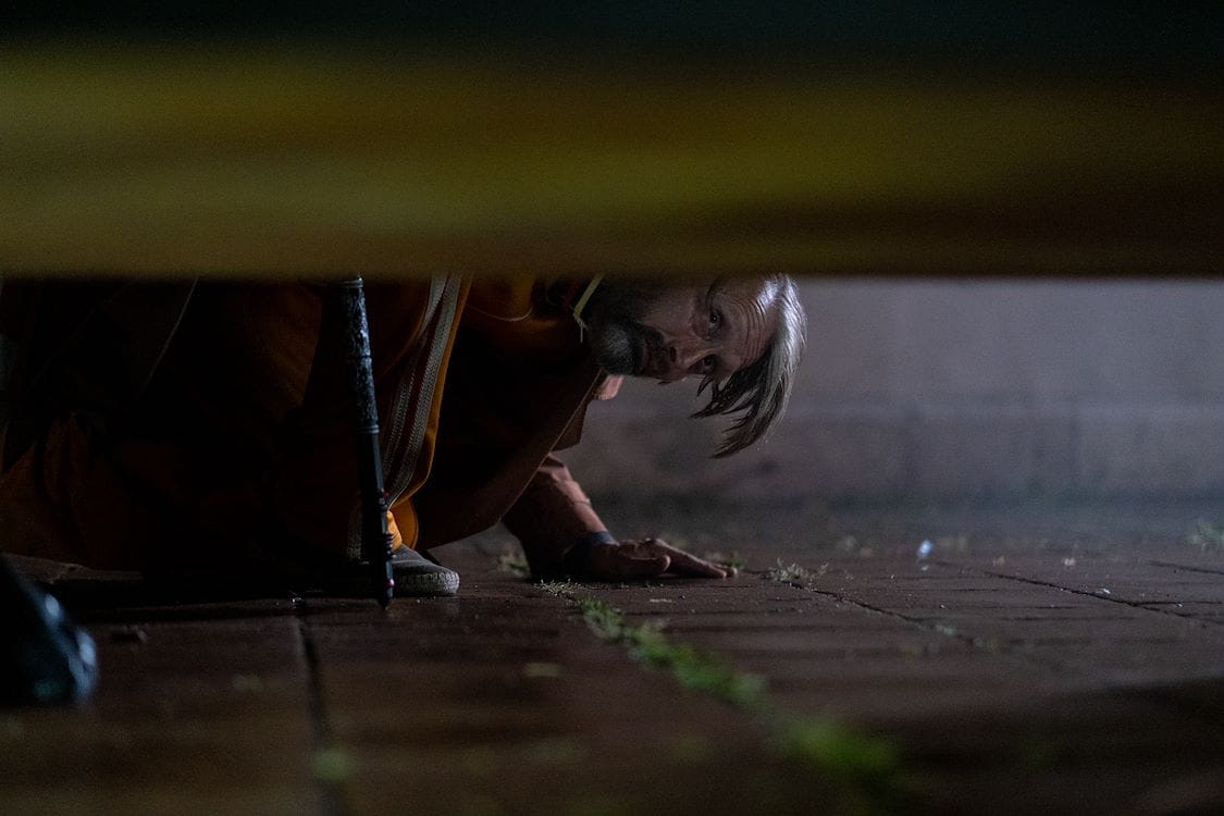 Mads Mikkelsen zoekt naar dust bunnies onder een bed