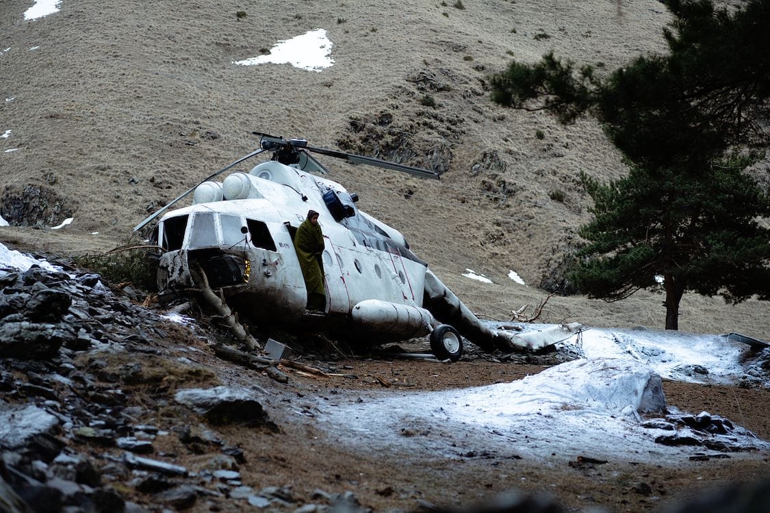 Ella Balinska stapt uit een gecrashte heicopter in een berglandschap in Georgie. Een scène uit de film The Occupant
