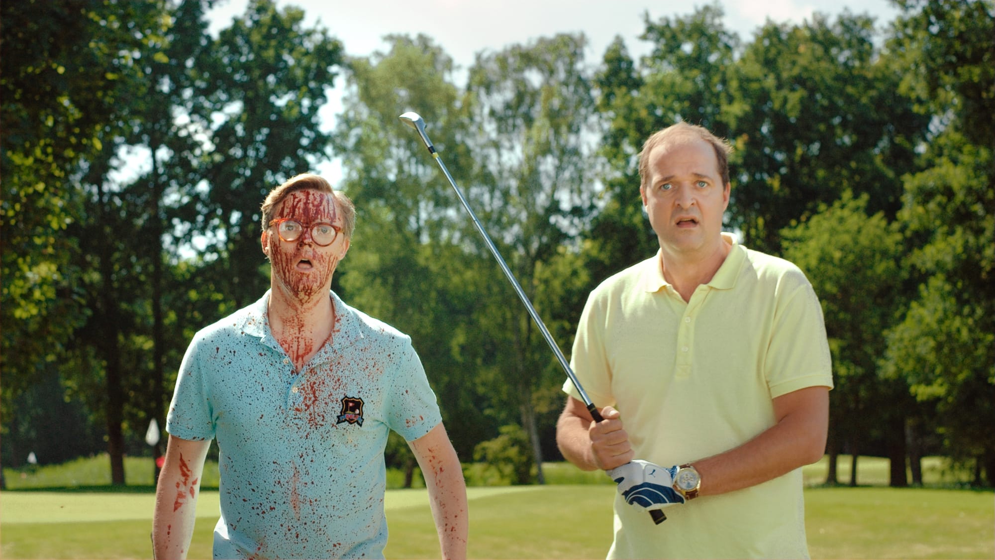 Afbeelding van twee bebloede golfers die verschrikt kijken naar iets buiten het beeld van de camera. Uit de film Prooi.