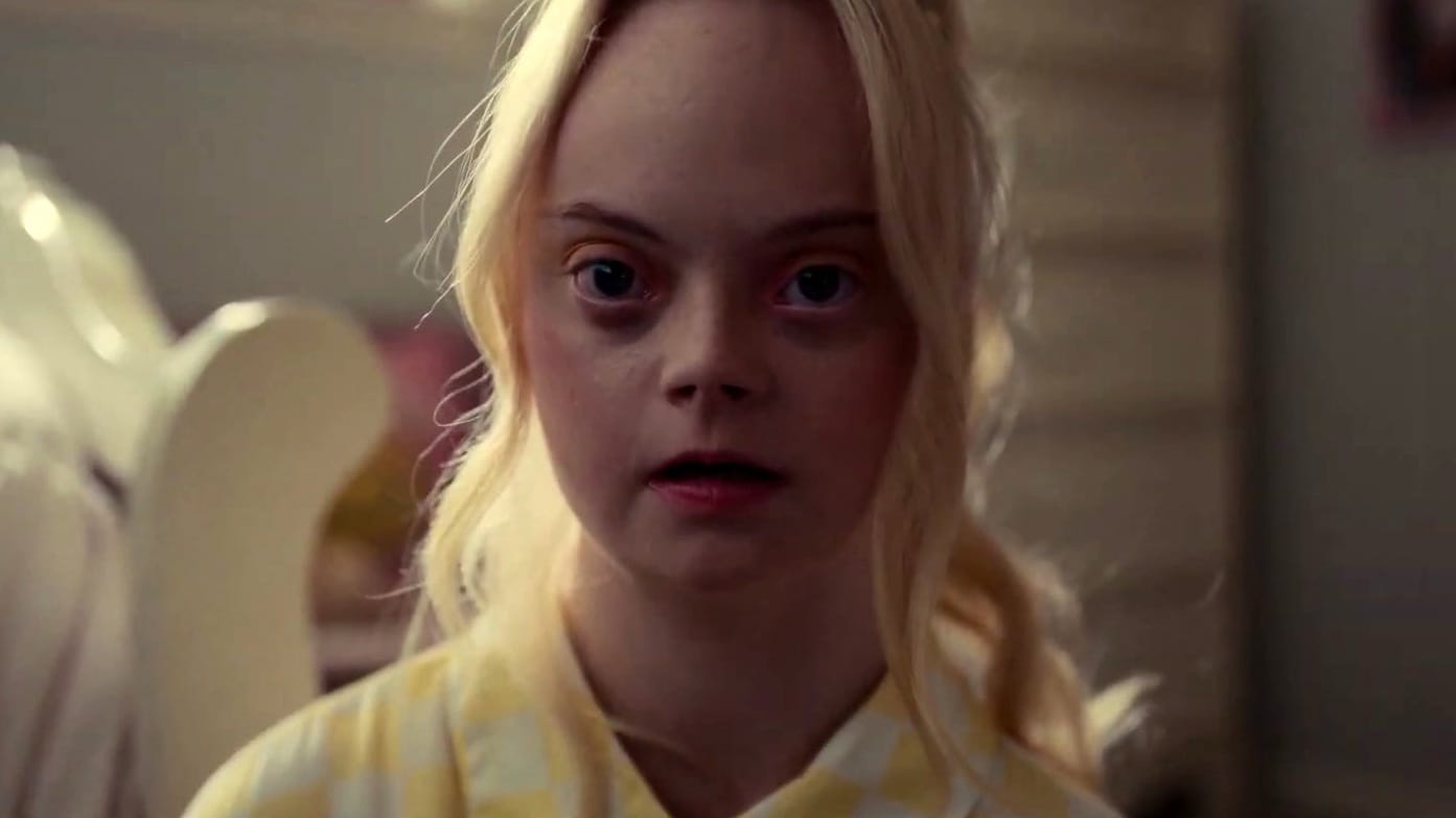 Een afbeelding van een blond meisje met downsyndroom die recht in de camere kijkt, uit de film The Other