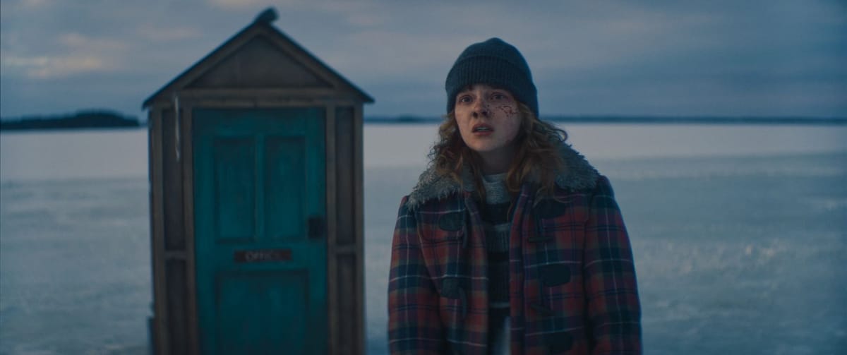 Laurel Marsden in een scène van Dead of Winter op een kale sneeuwvlakte voor een klein hutje