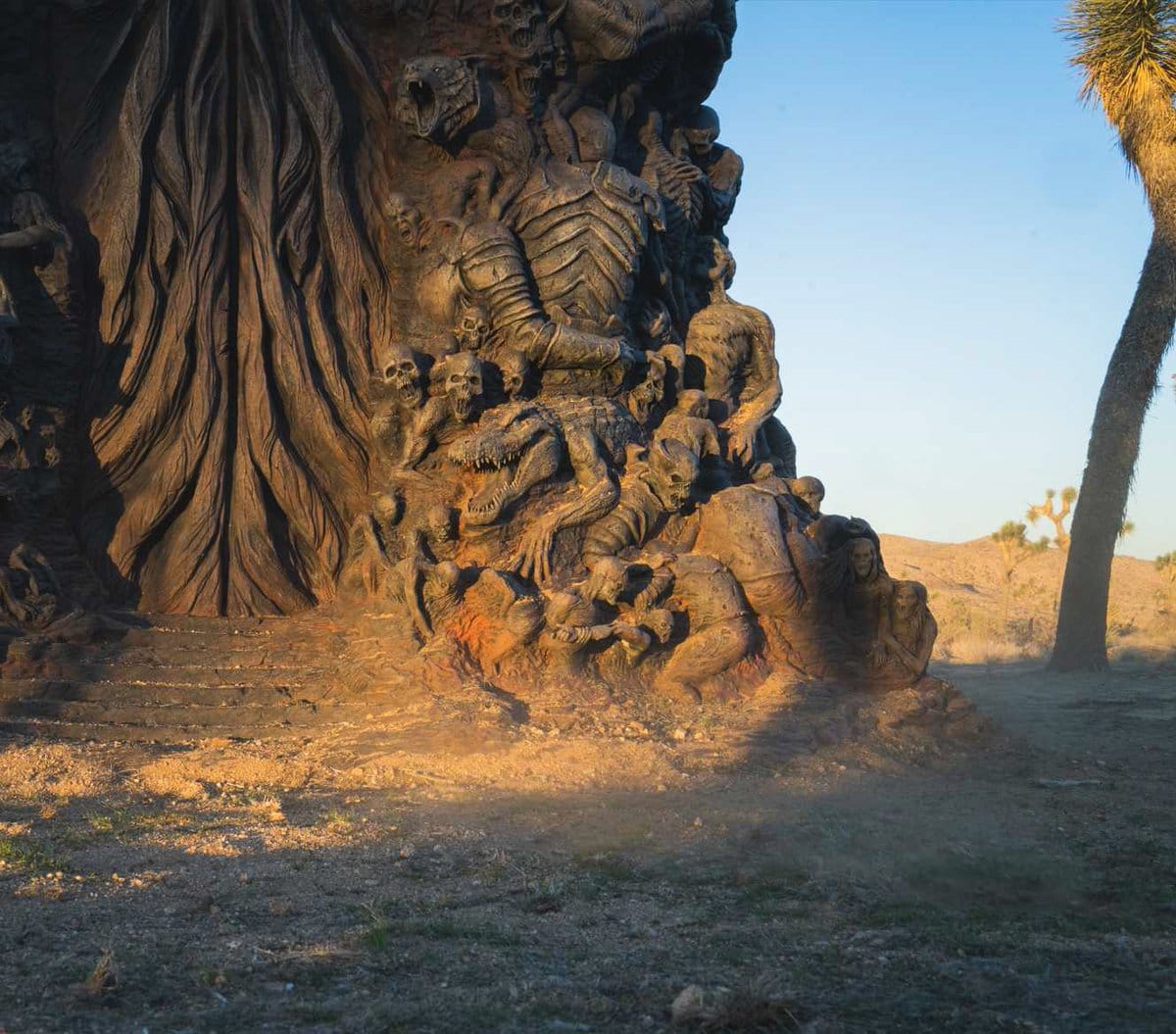 Een afbeelding van een mysterieus standbeeld in de woestijn met monsterachtige vormen erin.