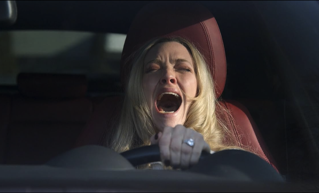Een afbeelding van een schreeuwende vrouw achter het stuur.
