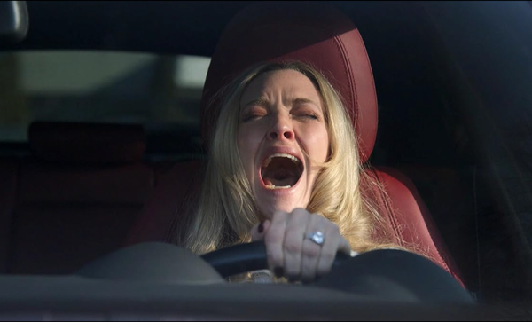 Een afbeelding van een schreeuwende vrouw achter het stuur.