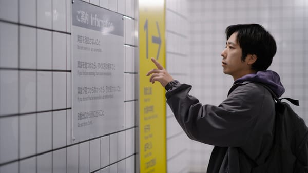 Een afbeelding van een Japanse man die informatie leest op het metrostation, uit de film Exit 8